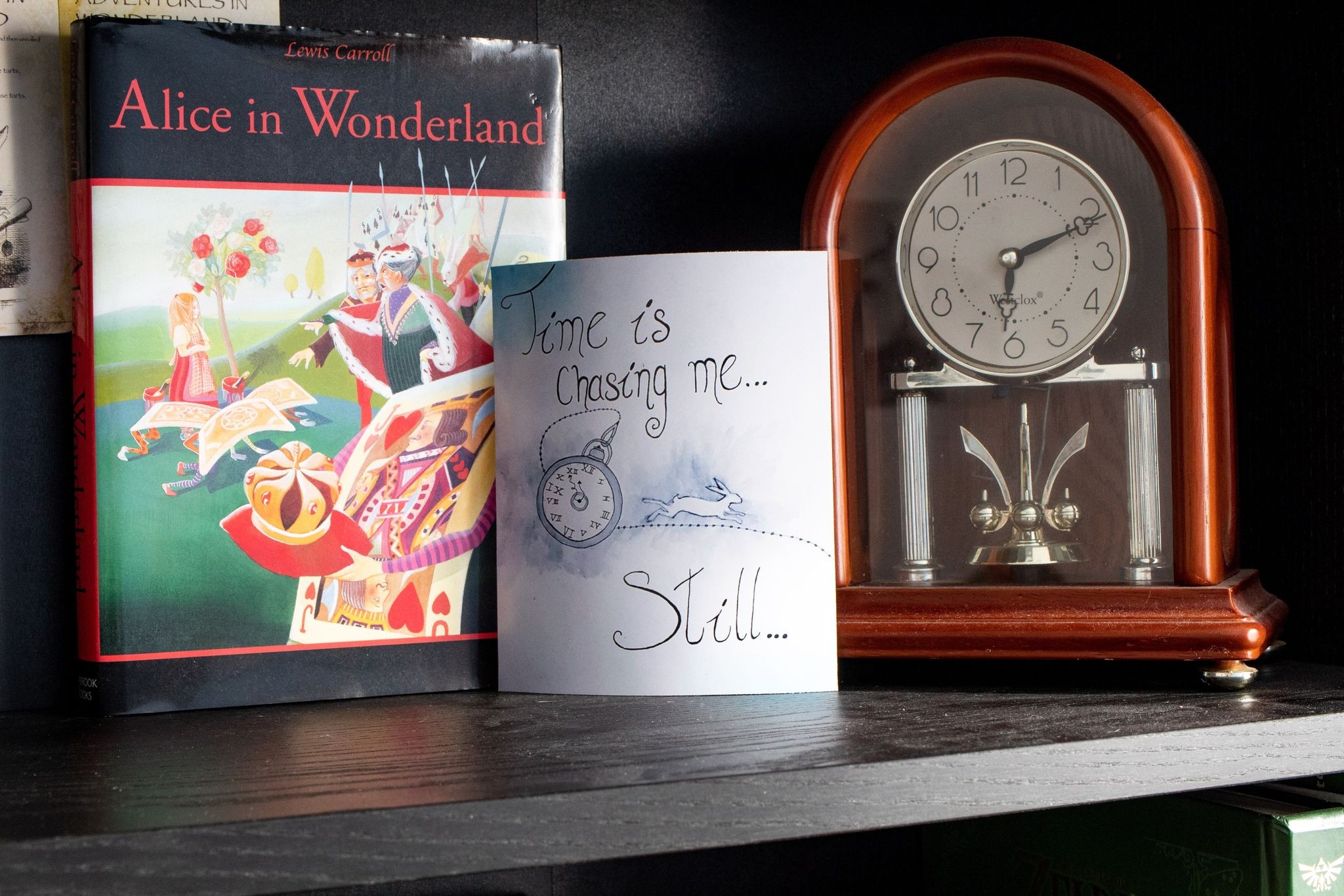 Product image of "Time is Chasing Me" print one  a bookshelf sitting in between an old fashioned clock and a copy of Alice in Wonderland by Lewis Carroll