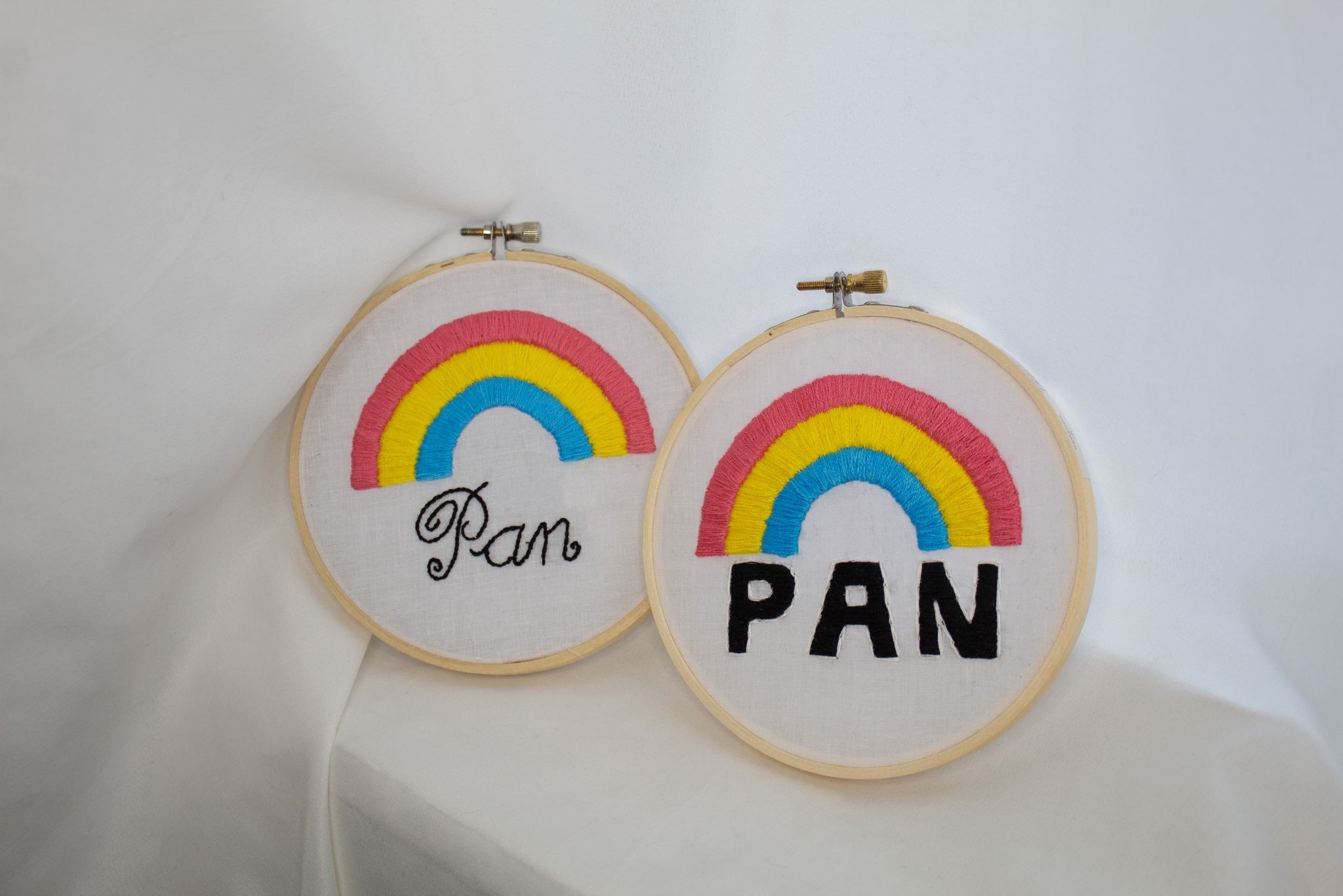 Product image of both the Italic Pan Pride and the Bold Pan Pride embroideries set against a white curtain backdrop