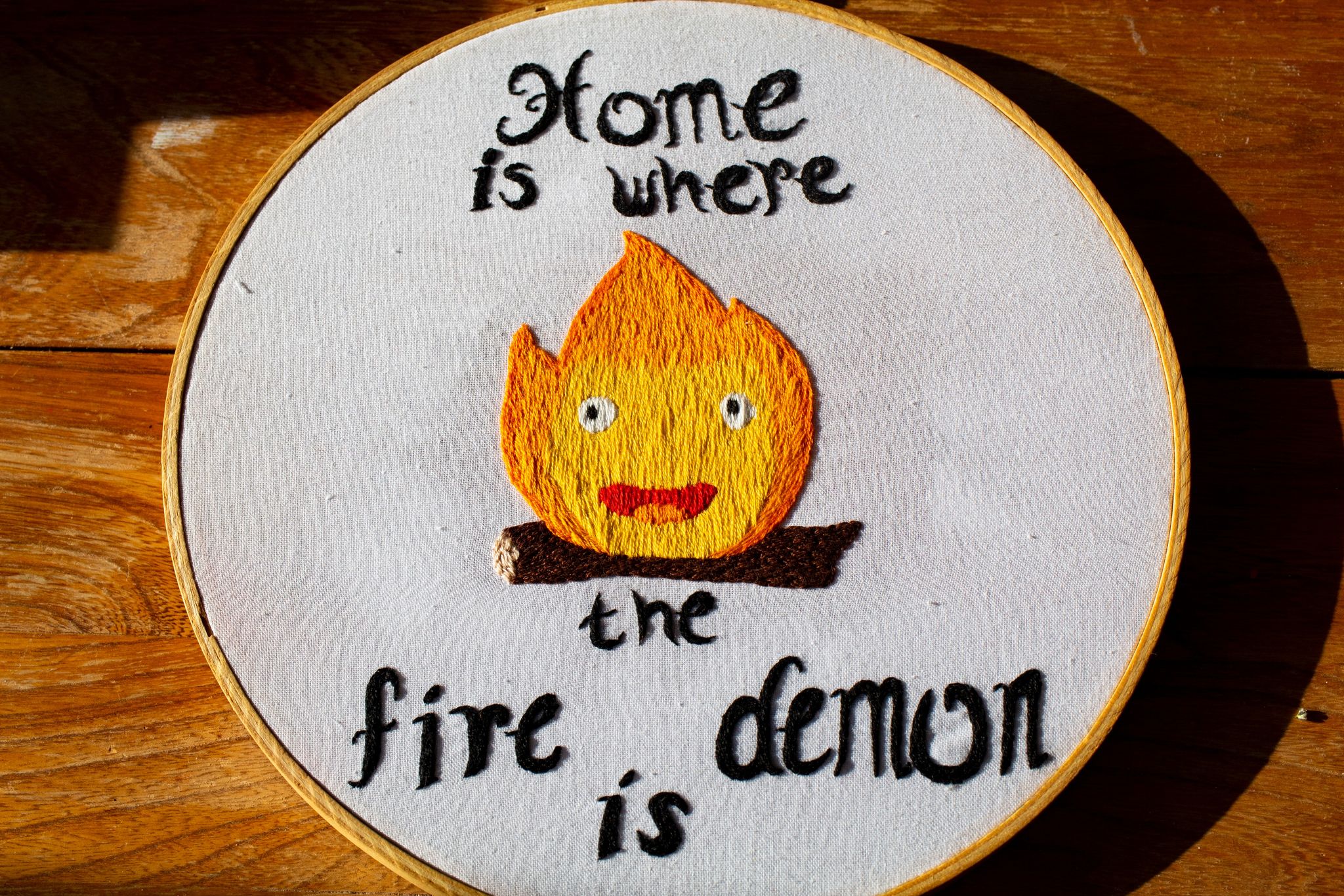 Product image of Calcifer embroidery on a wooden background