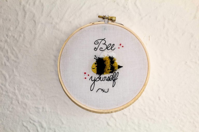 Product image of "Bee Yourself" embroidered bumble bee hung up on a white wall
