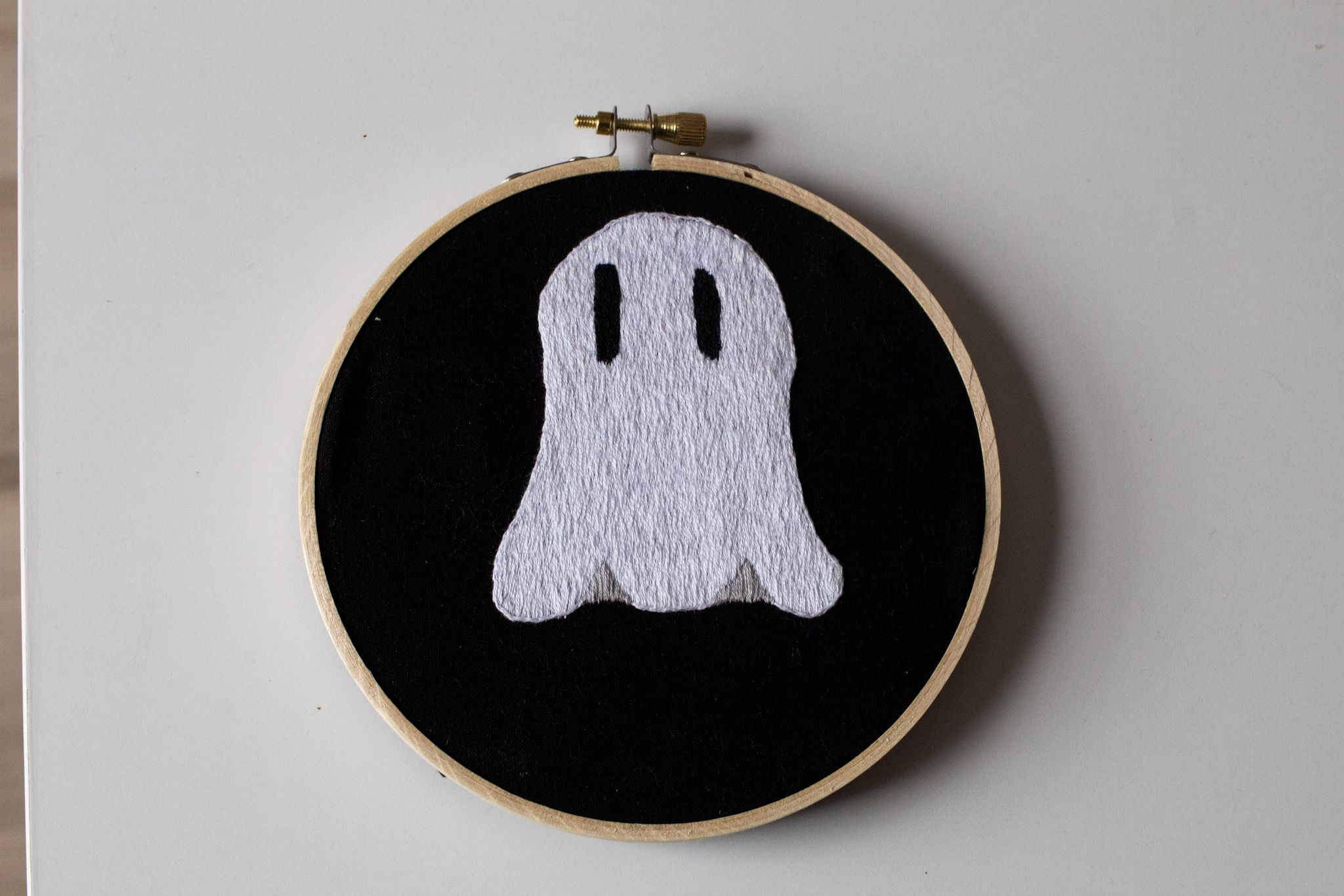 Product image of "Lonely Ghostie" embroidered ghost hung up on a white wall