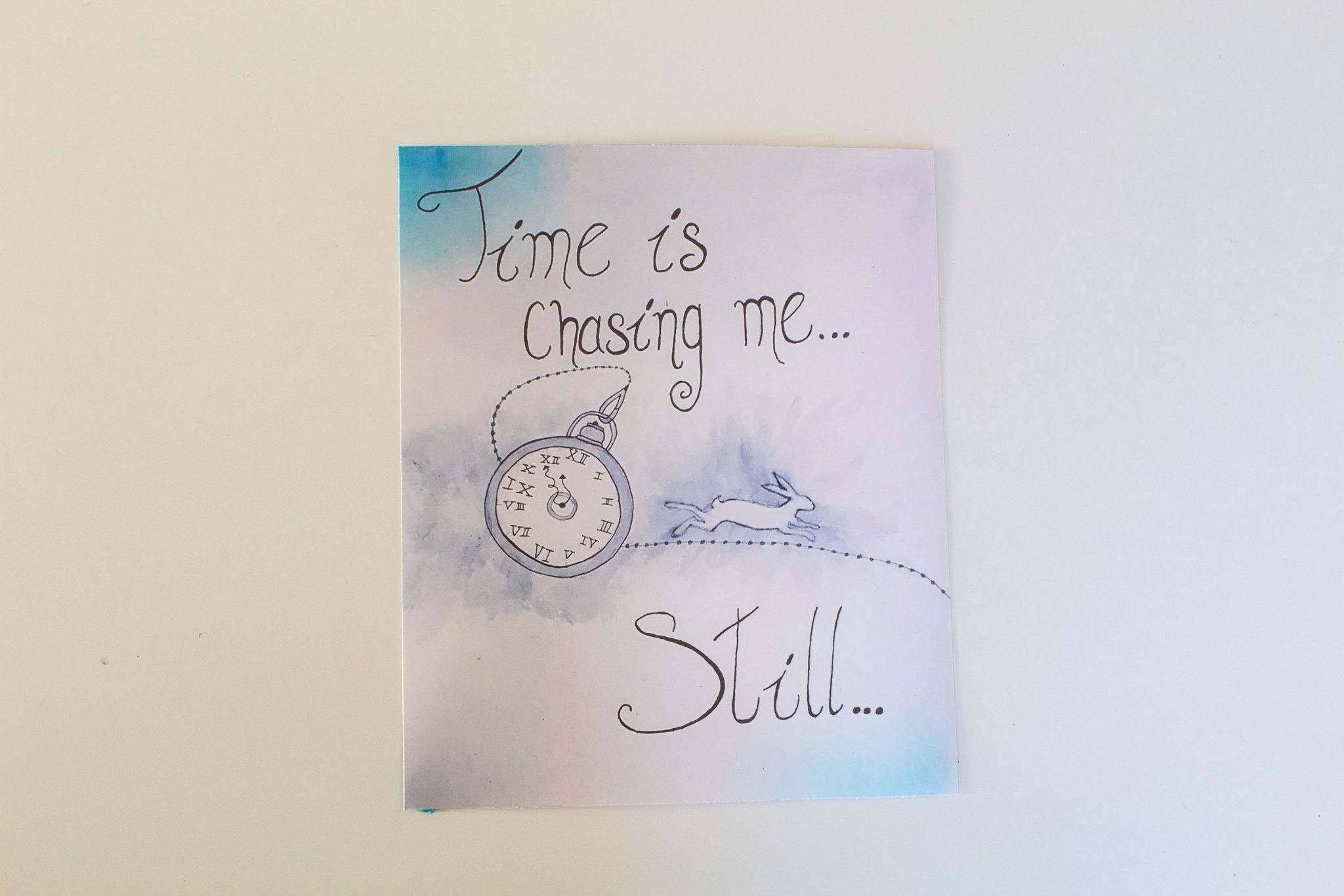 Product image of a print depicting a pocket watch and an outline of a white rabbit running away with the words "Time is Chasing me... Still", set on a cloudy white back ground with splashes of blue and grey