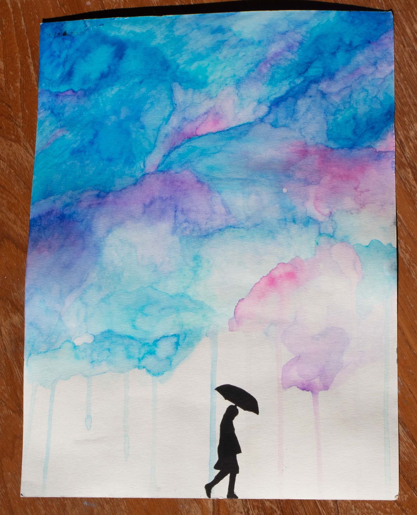 Close up product image of a watercolour painting of blue and pink clouds raining onto the silhouette of a person holding an umbrella,